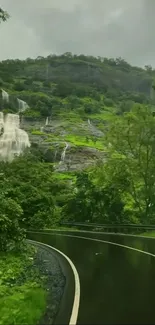 Serene landscape with waterfall and lush greenery along a winding road.