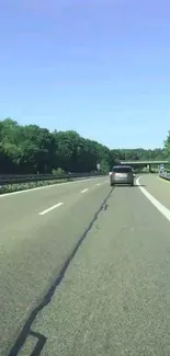 Scenic highway with lush green trees and a clear blue sky.