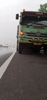 Truck parked on a rainy highway road with misty atmosphere.