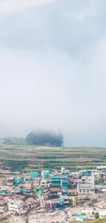 Scenic view of hill town with mist and green fields.