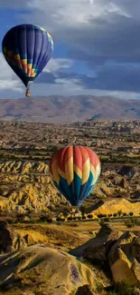 Hot air balloons float over scenic landscape under a clear blue sky.