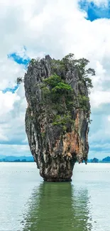 Tropical island with tall rock and lush foliage.