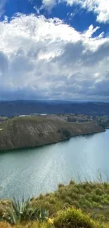 Scenic view of a lake beneath a vibrant cloudy sky, surrounded by green hills.