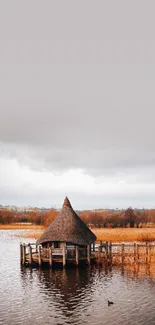 A peaceful lake hut surrounded by tranquil water under a cloudy sky.