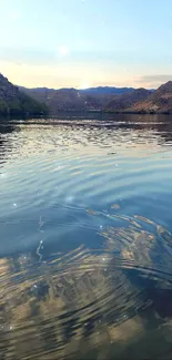 Peaceful lake with mountain reflections under a clear sky.