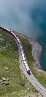 A train passes by a turquoise lake with a scenic mountain view.