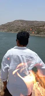 Serene lake with scenic backdrop and man overlooking the view.