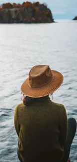 Person with hat admiring a peaceful lake view with trees.