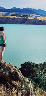 Hiker overlooks a vast blue lake with mountains in the background.