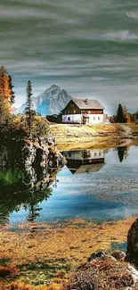 Scenic lakeside cabin with autumn trees and mountain reflection.