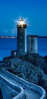 Lighthouse on rocky shore at twilight, calm ocean backdrop.