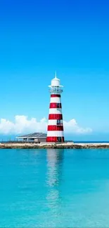 Lighthouse by a serene beach with clear blue sky and calm waters.