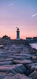 Lighthouse at the end of a rocky path during sunset by the coast, under a vivid sky.