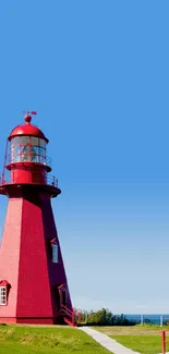 Red lighthouse and house under a clear blue sky.