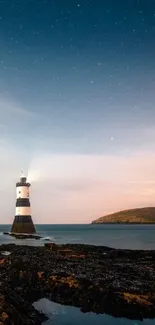 Lighthouse under a starry night sky with calm coastal waters.