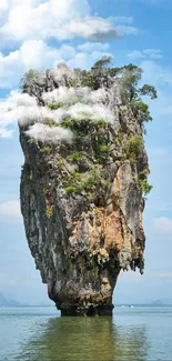 Limestone island rising from calm blue ocean under a clear sky.