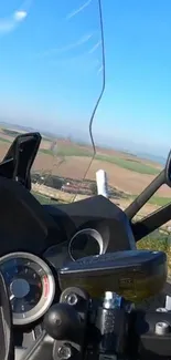 Motorcycle ride on open road with scenic view of fields and blue sky.