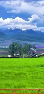 Mobile wallpaper with green fields, distant mountains, and blue sky.