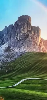 Mountain landscape with rainbow in blue sky.