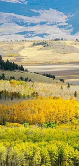 Autumn mountain landscape with yellow trees under blue sky.