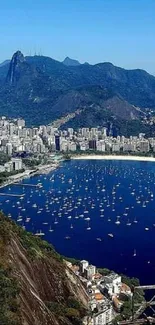 City nestled between mountains and blue bay with boats.