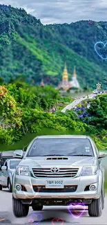 Vehicles on a scenic mountain road with lush greenery and vibrant hearts.