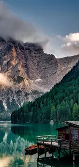 Serene mountain lake with cozy cabin and misty mountains.