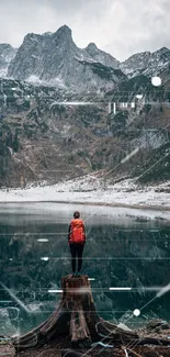 Traveler with red backpack by mountain lake, surrounded by nature.