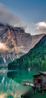 Rustic cabin by a tranquil mountain lake at sunset.