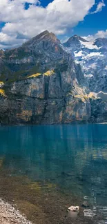 Scenic mountain lake with blue water and towering peaks under a cloudy sky.