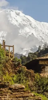 Scenic mountain path with a stone house and snowy peaks under a clear sky.