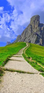 Scenic view of a mountain path under a blue sky with green grass.