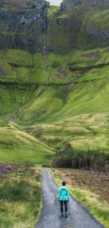 Traveler walking on lush green path towards mountains.