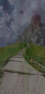 A scenic mountain path leads to a towering rocky peak under a vibrant sky.