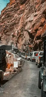 vehicles driving through rugged mountain road with towering cliffs