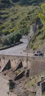 Classic car on winding mountain road with lush green surroundings.