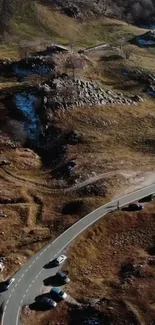 Aerial view of winding mountain road in winter landscape with earthy tones.