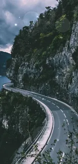 Scenic winding road on mountain edge with cloudy sky and lush scenery.