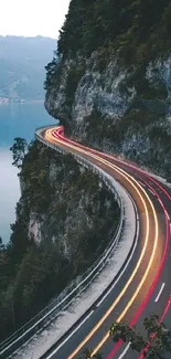 Scenic mountain road with light trails and lake view.