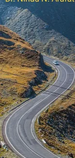 Scenic mountain road winding through rocky terrain under clear blue skies.