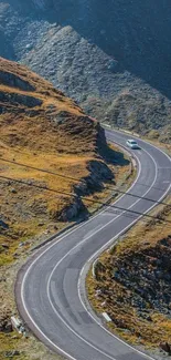 Winding road through mountains under a blue sky.