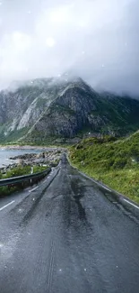 Misty mountain road with lush greenery and clouds.