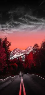 Road leading to mountains under a red sky with trees on the side.