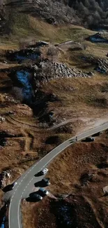 Aerial view of winding road through a rugged mountain landscape, perfect mobile wallpaper.