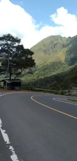 Scenic road curving through lush green mountains under a blue sky.