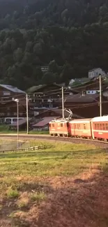 Train passing through a scenic mountain village at sunset.