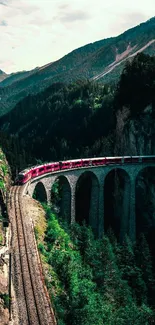 Red train crossing a scenic mountainside bridge.