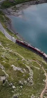 A train travels through mountain terrain beside a scenic azure lake.