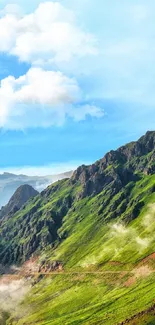 Scenic mountain valley with blue sky and lush green hills wallpaper.