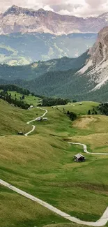 Scenic green valley with winding road and mountain backdrop.